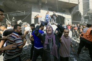 EDITORS NOTE: Graphic content / A Palestinian woman reacts as others rush to look for victims in the rubble of a building following an Israeli strike in Khan Yunis in the southern Gaza Strip on October 17, 2023, amid the ongoing battles between Israel and the Palestinian group Hamas. One month after Israel was wracked by Hamas attacks, life has been upended for both the Palestinians and Israel after it launched a war of reprisal in the Gaza Strip. The October 7 attacks by Hamas militants who stormed across from Gaza and struck kibbutzim and southern Israeli areas killed 1,400 people, mostly civilians, and deeply scarred the nation. The health ministry in Hamas-run Gaza says nearly 9,500 have been killed, two-thirds of them women and children, and mostly civilians. (Photo by Mahmud HAMS / AFP)